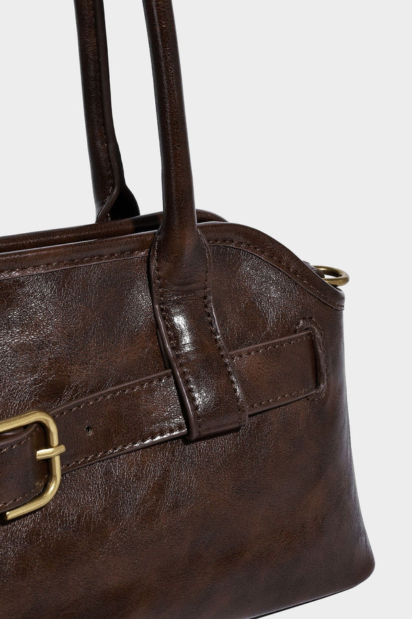 Strukturierte dunkelbraune Henkeltasche mit Öl-Wachs-Finish, vorderer Gürtelschnalle, goldfarbenen Beschlägen und zwei Tragegriffen, Detailansicht