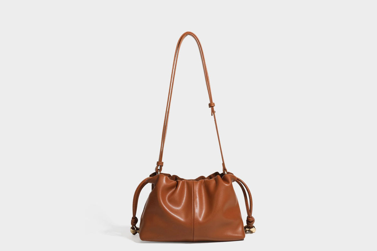 Suede-look drawstring shoulder bag in brown with smooth trim, knotted bead drawstring closure, slim adjustable strap, and