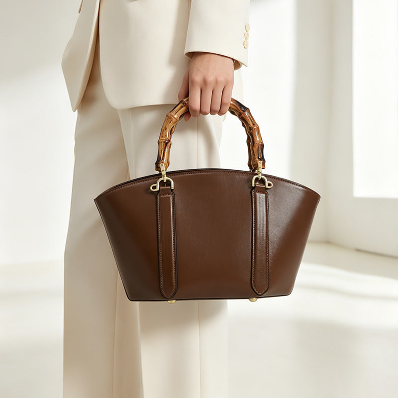 Structured trapezoid handbag with segmented bamboo top handle, smooth leather-look finish, gold-tone hardware, and vertical
