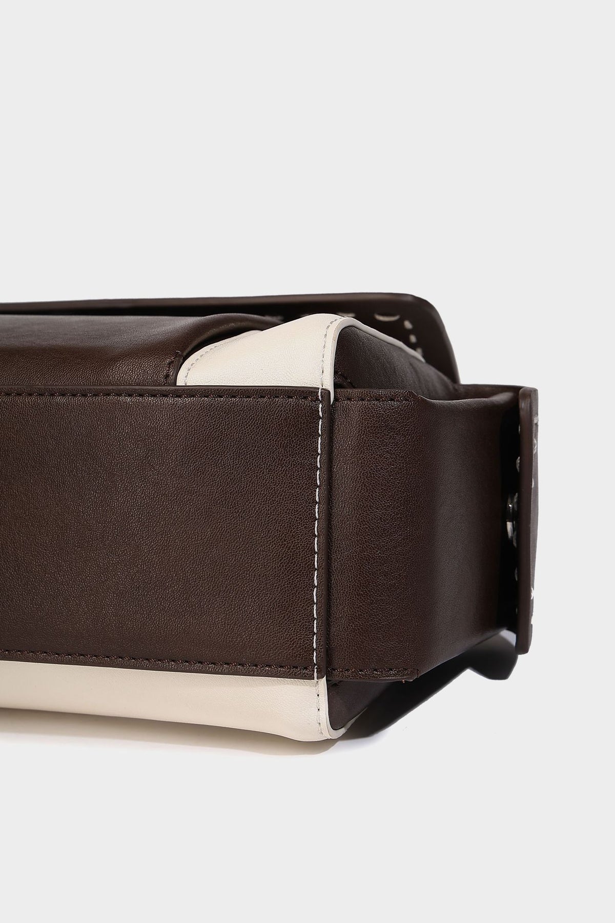 Structured flap crossbody bag in dark brown and cream color-block with white contrast stitching, adjustable shoulder strap