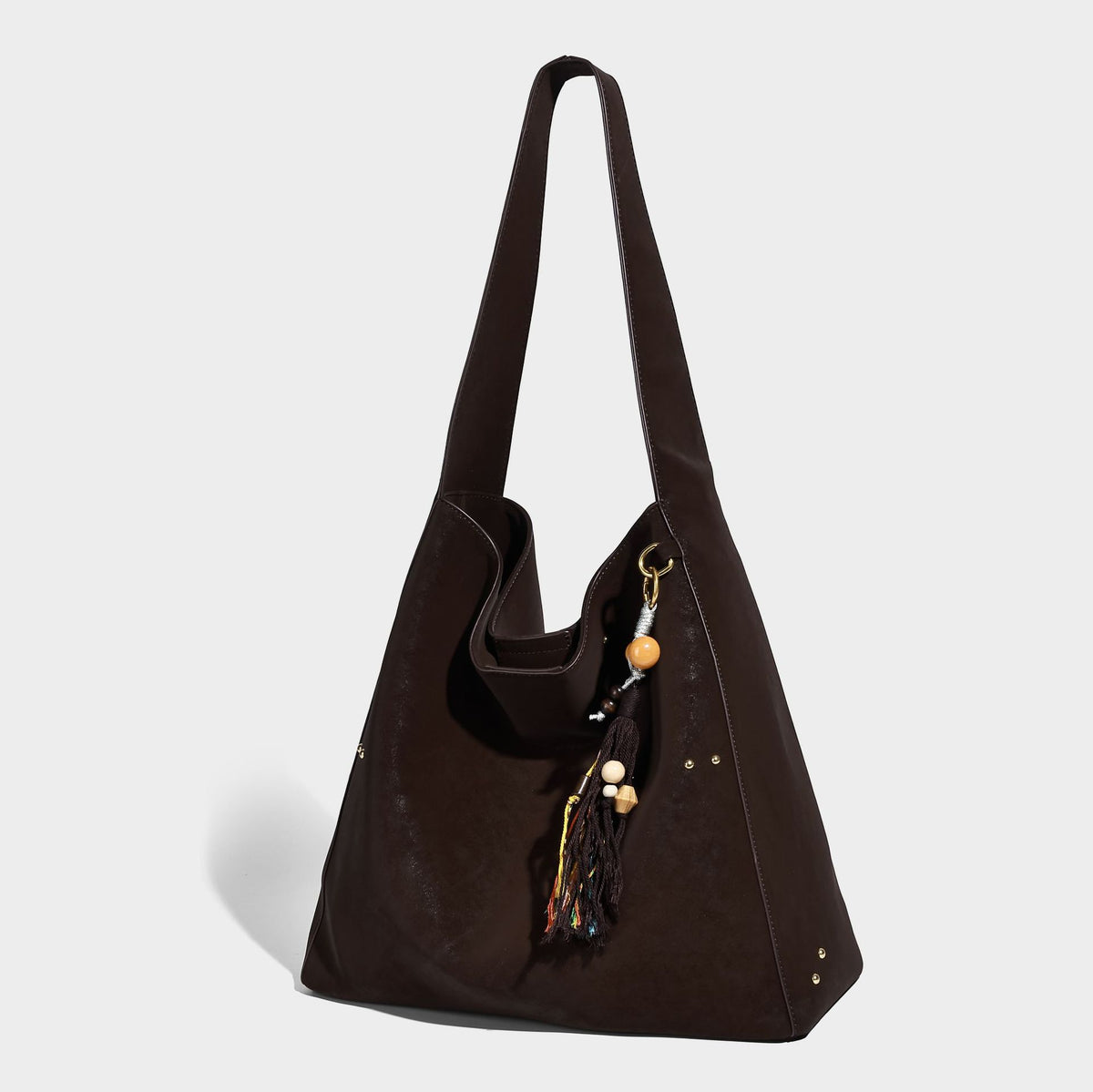 Oversized trapezoid tote bag with matte leather-look finish, gold-tone rivets, and long shoulder strap, front view