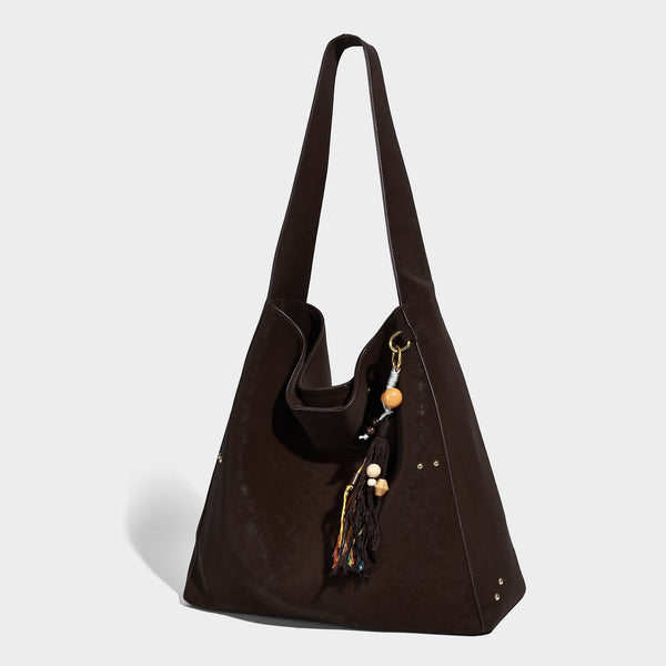 Oversized trapezoid tote bag with matte leather-look finish, gold-tone rivets, and long shoulder strap, front view