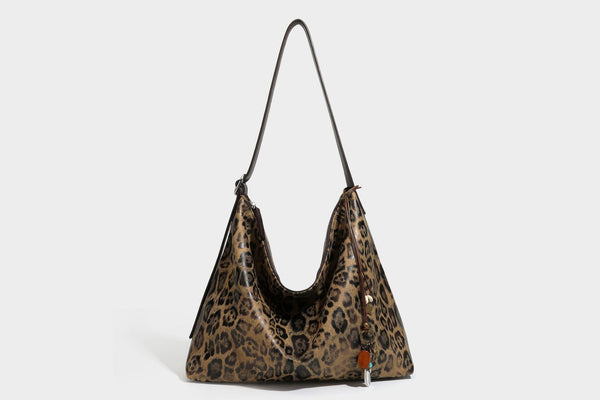 Slouchy leopard print hobo shoulder bag with glossy coated finish, top zipper closure, dark brown trim, and dangling charm