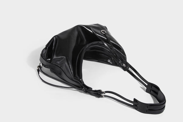 Glossy black slouchy hobo shoulder bag with zip closure, silver-tone ring hardware, and adjustable crossbody strap, detail