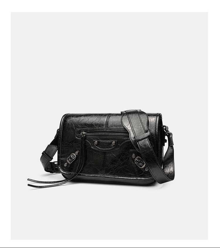 Small structured rectangular crossbody bag with crinkle leather-look finish, front zip pocket, gunmetal stud hardware, and