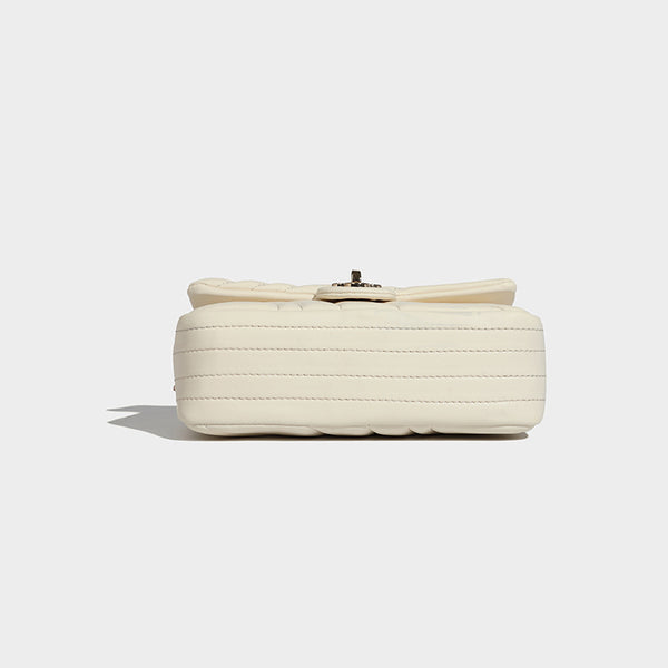 Compact cream quilted flap crossbody bag with wave stitching, gold-tone chain strap, and four-petal turn-lock clasp, detail