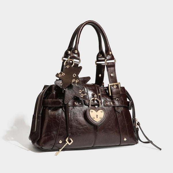 Structured leather-look satchel bag with heart padlock charm, star charm, gold-tone buckle hardware, dual top handles, and