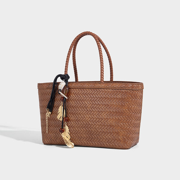 Structured chevron woven leather-look tote bag with braided top handles, gold feather charm, and adjustable shoulder strap