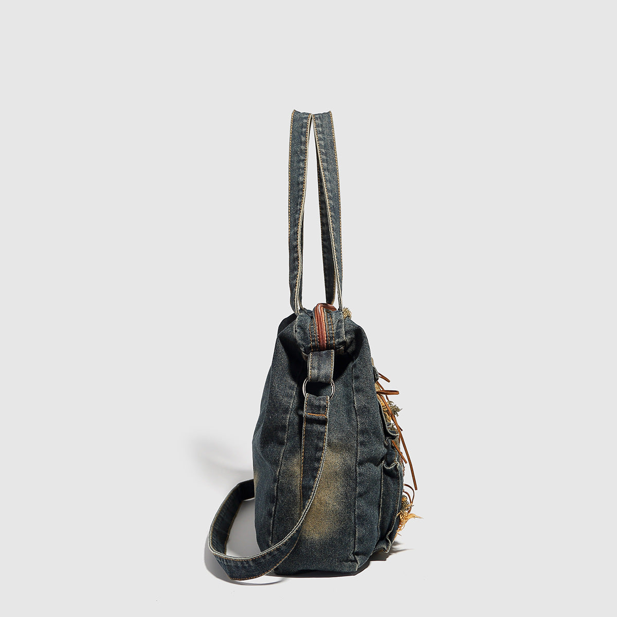 Large distressed denim patchwork shoulder tote bag with frayed panels, leather-look lace detailing, and front zip pocket in