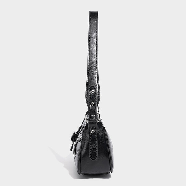 Compact moto-inspired shoulder bag with crisscross grommet strap detail, glossy textured finish, and adjustable crossbody