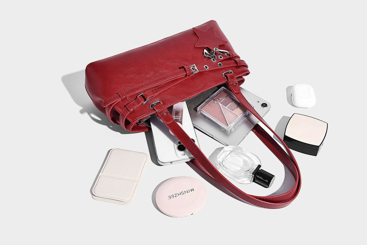 Structured glossy leather-look shoulder bag with wraparound belt straps, silver-tone hardware, and dangling star charm
