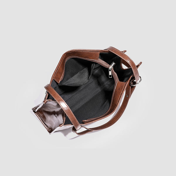 Large structured glossy leather-look tote bag with dual top handles and long shoulder strap in burnished brown, detail view 4