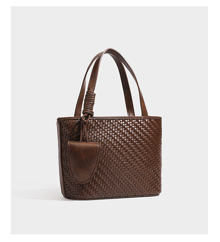 Strukturierte Tote Bag mit gewebter Oberfläche in Braun, goldfarbenen Metalldetails, seilumwickelten Tragegriffen, einer kleinen Fronttasche und weiteren Details