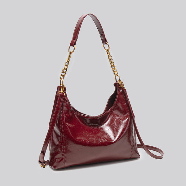 Glossy leather-look hobo shoulder bag with gold-tone chain-and-leather strap in deep burgundy red, detail view 3