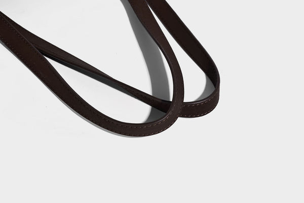 Structured trapezoid shoulder tote in dark brown matte suede-look finish with dual straps, wraparound belt bands