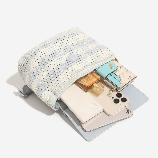 Small structured woven-body flap bag with smooth leather-look front panel, knotted top handle, and wide adjustable shoulder