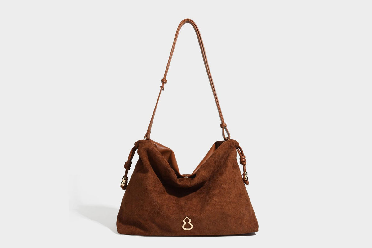 Suede-look drawstring shoulder bag in brown with smooth trim, knotted bead drawstring closure, slim adjustable strap, and