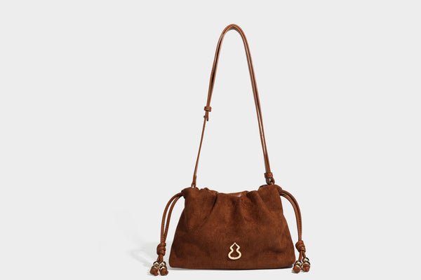 Suede-look drawstring shoulder bag in brown with smooth trim, knotted bead drawstring closure, slim adjustable strap, and