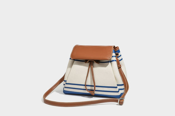 Cream canvas bucket bag with blue horizontal stripes, tan leather-look flap and trim, drawstring closure, silver-tone, detail