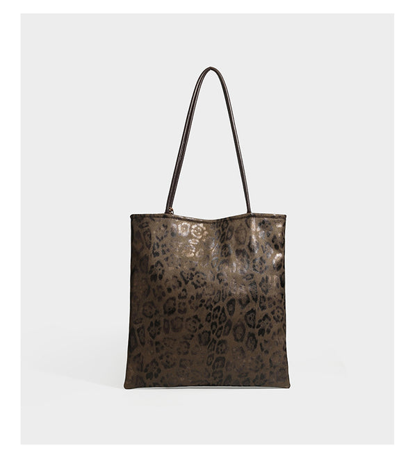 Large leopard print shoulder tote bag in tan and brown with slim dark straps and dangling beaded charm hardware, detail view