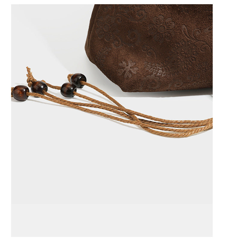 Slouchy boho hobo shoulder bag in embossed brown suede-look finish with beaded strap, cord tassels, and brass-tone leaf