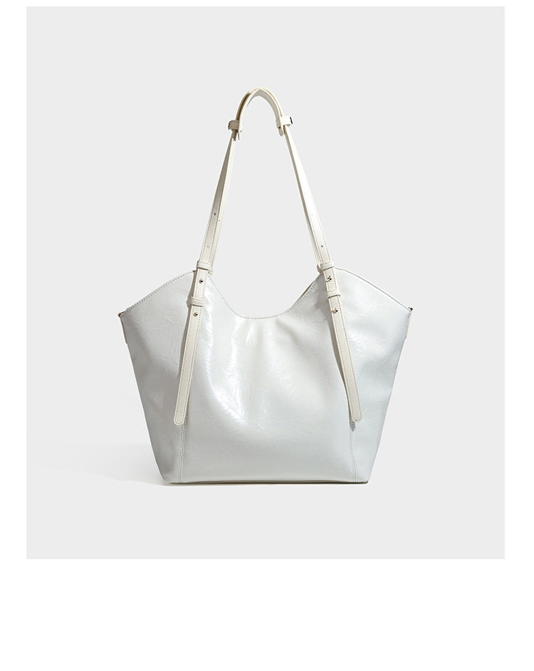 Große, glänzende Tote-Bag aus schwarzem Lederimitat mit geknitterter Optik, lässig fallender Trapezsilhouette, zwei Schulterriemen und goldfarbenen