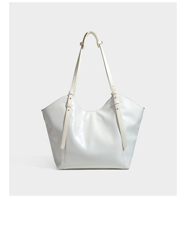 Große, glänzende Tote-Bag aus schwarzem Lederimitat mit geknitterter Optik, lässig fallender Trapezsilhouette, zwei Schulterriemen und goldfarbenen