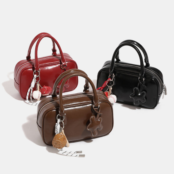 Kleine strukturierte Bowlingtasche in glänzender Lederoptik mit zwei Tragegriffen, abnehmbarem Schulterriemen und