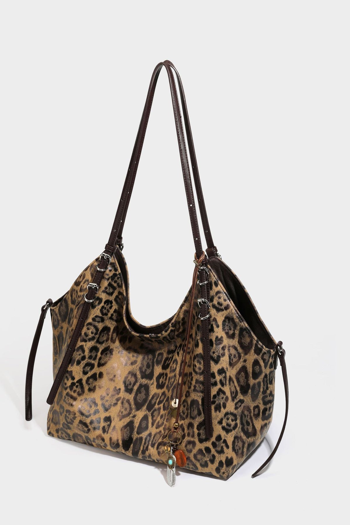 Slouchy leopard-print shoulder tote bag in tan and brown with long double straps, side tie straps, and dangling charm, detail
