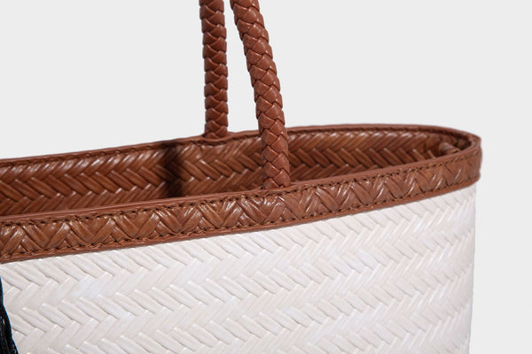 Structured woven-texture tote bag with brown braided top handles, decorative tassel charm, and detachable shoulder strap