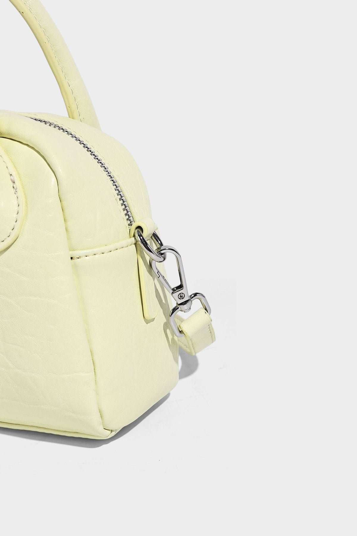 Mini-Tasche mit strukturierter Kuppelform und Tragegriff, in Pastellgelb mit genarbter Lederoptik, silberfarbenen Metallbeschlägen und abnehmbarem