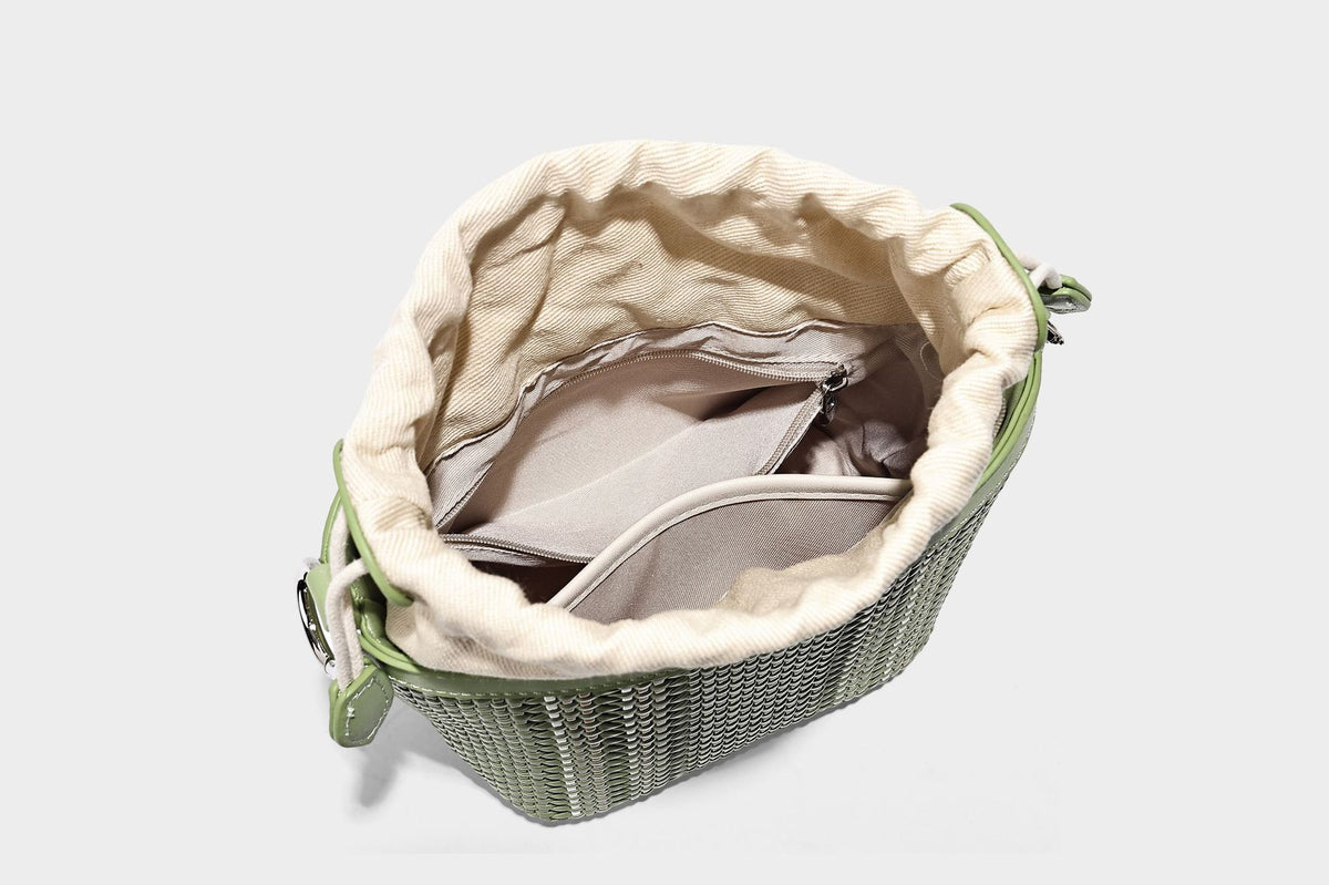 Small woven bucket bag with drawstring top, braided handle, detachable crossbody strap, and silver-tone ring hardware, detail