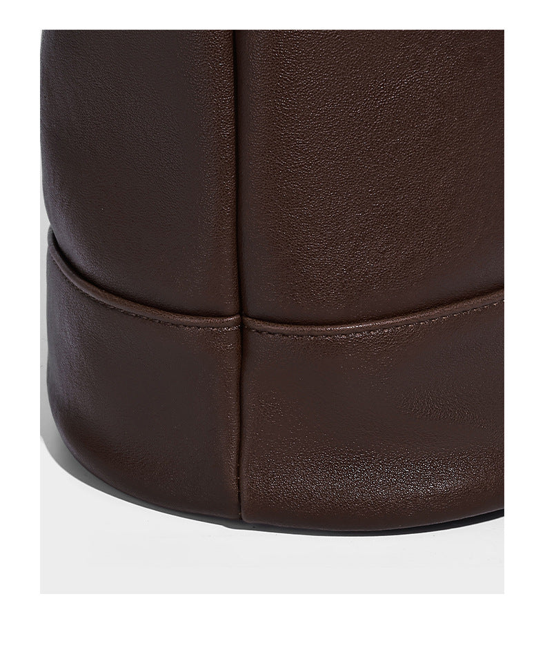 Slouchy bucket hobo shoulder bag in dark brown with glossy leather-look finish, top zip closure, and long adjustable, detail