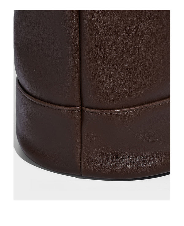 Slouchy bucket hobo shoulder bag in dark brown with glossy leather-look finish, top zip closure, and long adjustable, detail