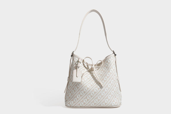 Woven geometric bucket shoulder bag in white and dark brown two-tone pattern with leather-look trim and drawstring top