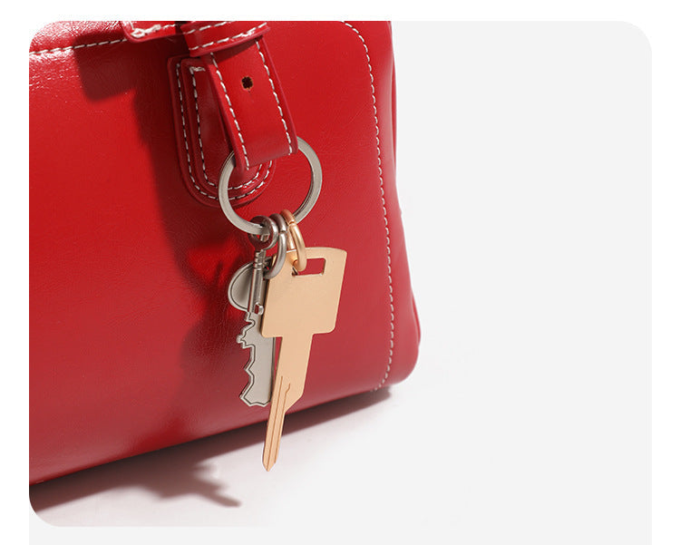 Strukturierte, glänzende rote Boston-Handtasche mit zwei Tragegriffen, kontrastierenden Ziernähten, Reißverschluss und silberfarbenen Details