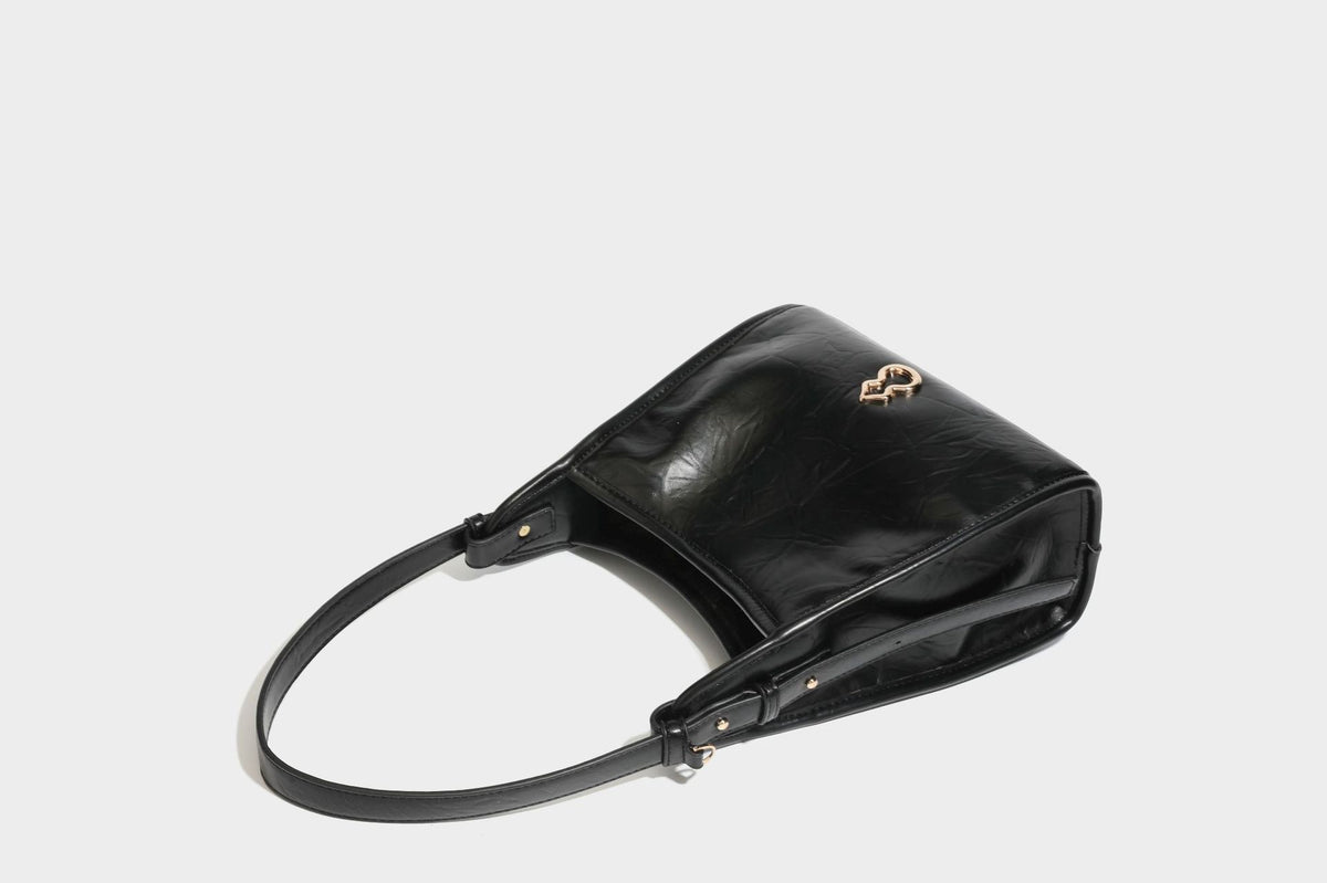 Strukturierte, trapezförmige Schultertasche aus glänzender, geknautscht wirkender Lederoptik mit goldfarbenen Beschlägen auf der Vorderseite und langem, verstellbarem