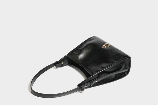 Strukturierte, trapezförmige Schultertasche aus glänzender, geknautscht wirkender Lederoptik mit goldfarbenen Beschlägen auf der Vorderseite und langem, verstellbarem