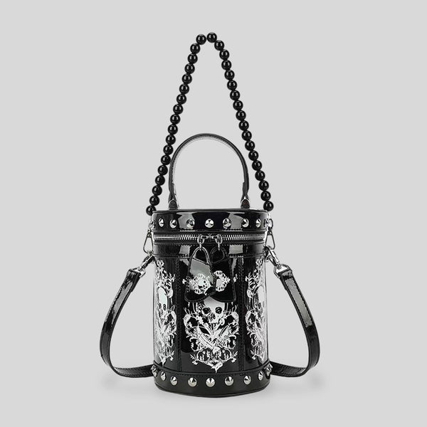 Black glossy cylindrical barrel bag with white skull-floral print panels, silver pyramid studs, black beaded top handle, and