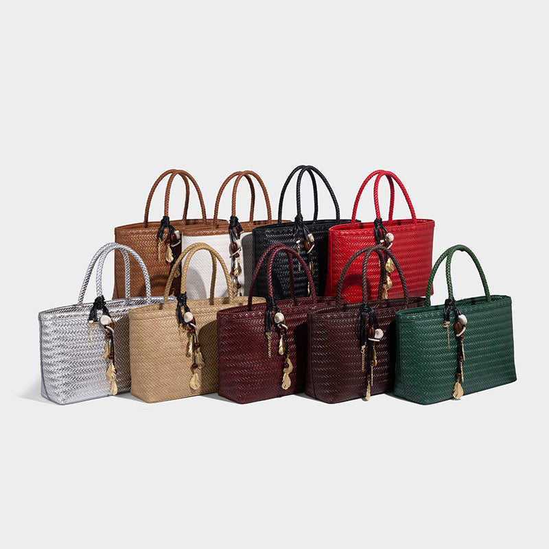 Structured woven-texture tote bag with brown braided top handles, decorative tassel charm, and detachable shoulder strap