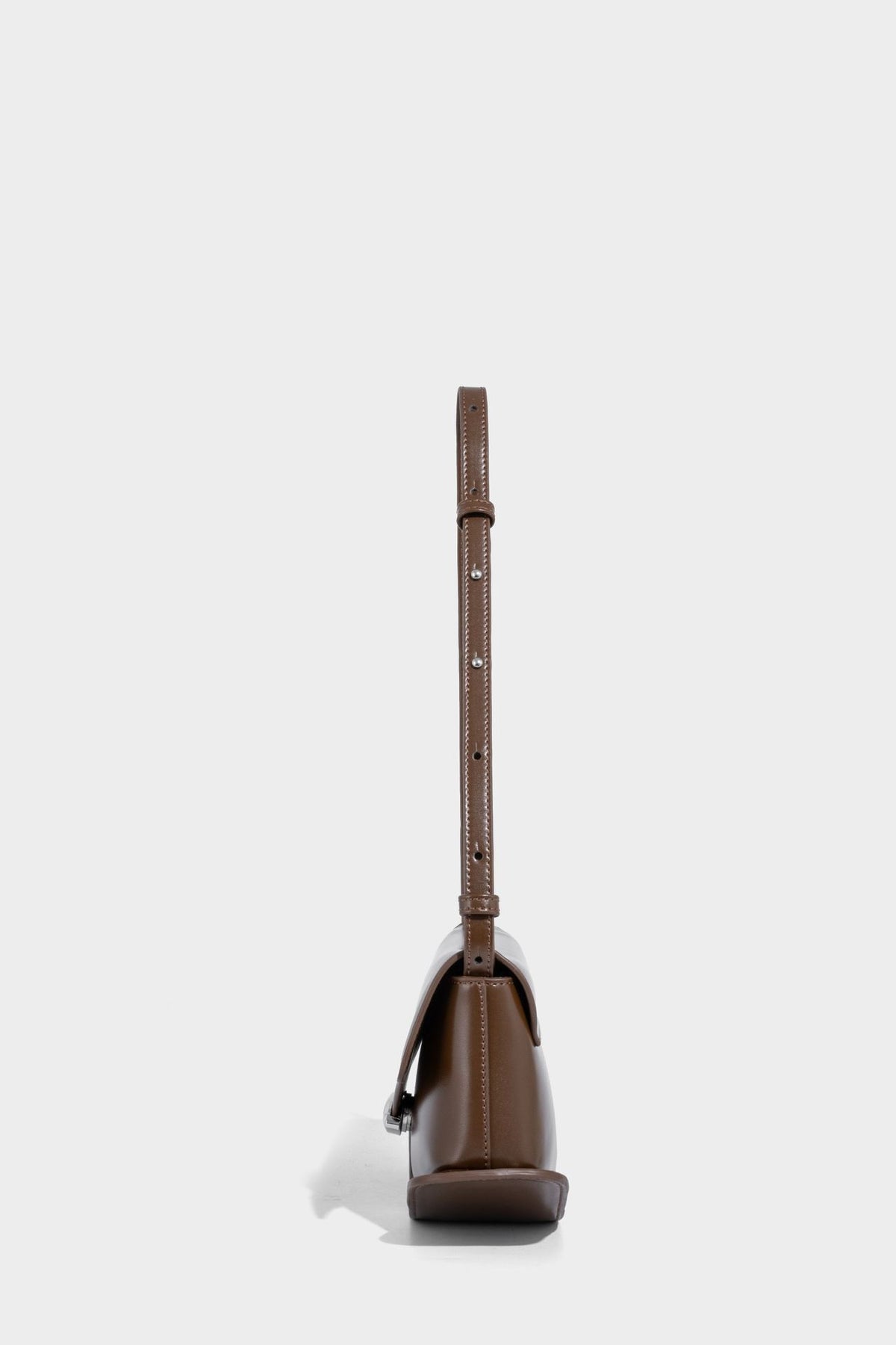 Small structured saddle bag with glossy leather-look finish, angular flap front, silver-tone metal clasp, and slim