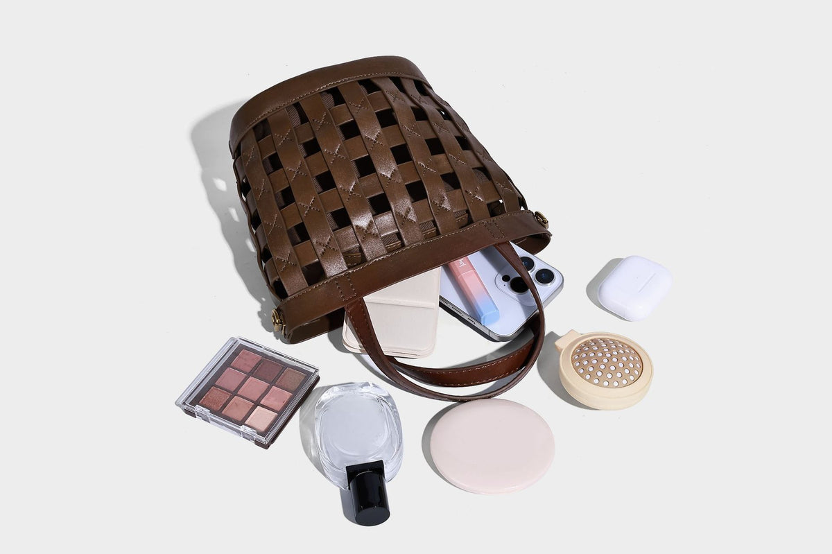 Small woven lattice bucket bag in brown leather-look finish with beaded tassel charm, dual top handles, and detachable