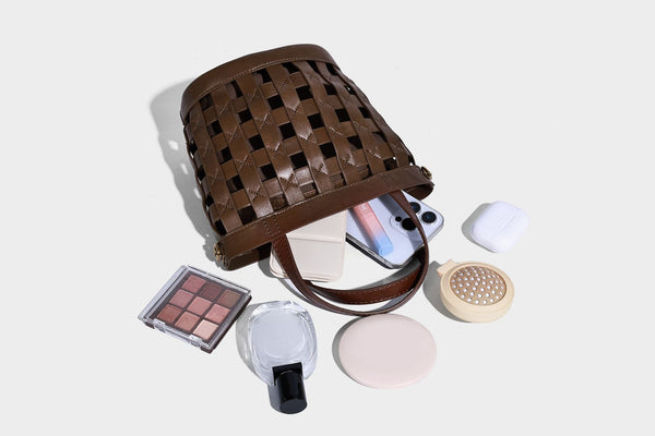 Small woven lattice bucket bag in brown leather-look finish with beaded tassel charm, dual top handles, and detachable