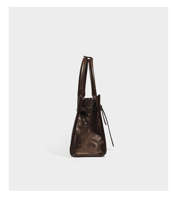 Structured leopard-print tote bag with glossy satin-like finish, dual rounded top handles, silver buckle-and-ring front