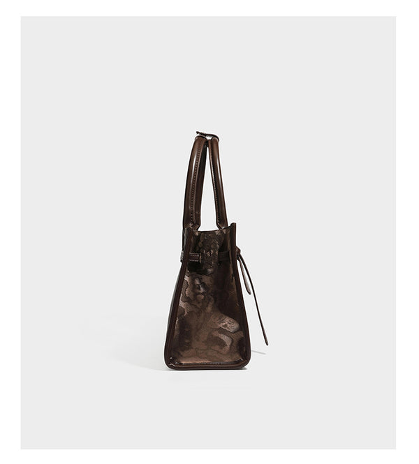Structured leopard-print tote bag with glossy satin-like finish, dual rounded top handles, silver buckle-and-ring front