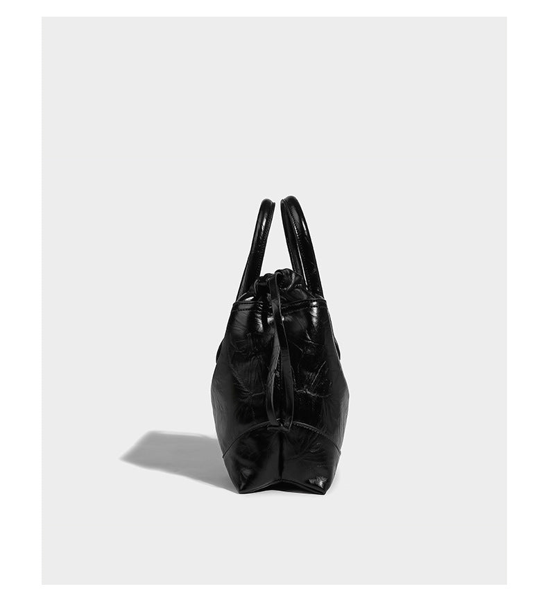 Glossy crinkled ruched drawstring bucket bag with rounded double top handles and detachable chain crossbody strap, detail