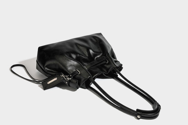 Glänzende schwarze, weich fallende Schultertasche mit gerafftem Abschluss, zwei langen Trageriemen, silberfarbenen Beschlägen und abnehmbarem Umhängeriemen