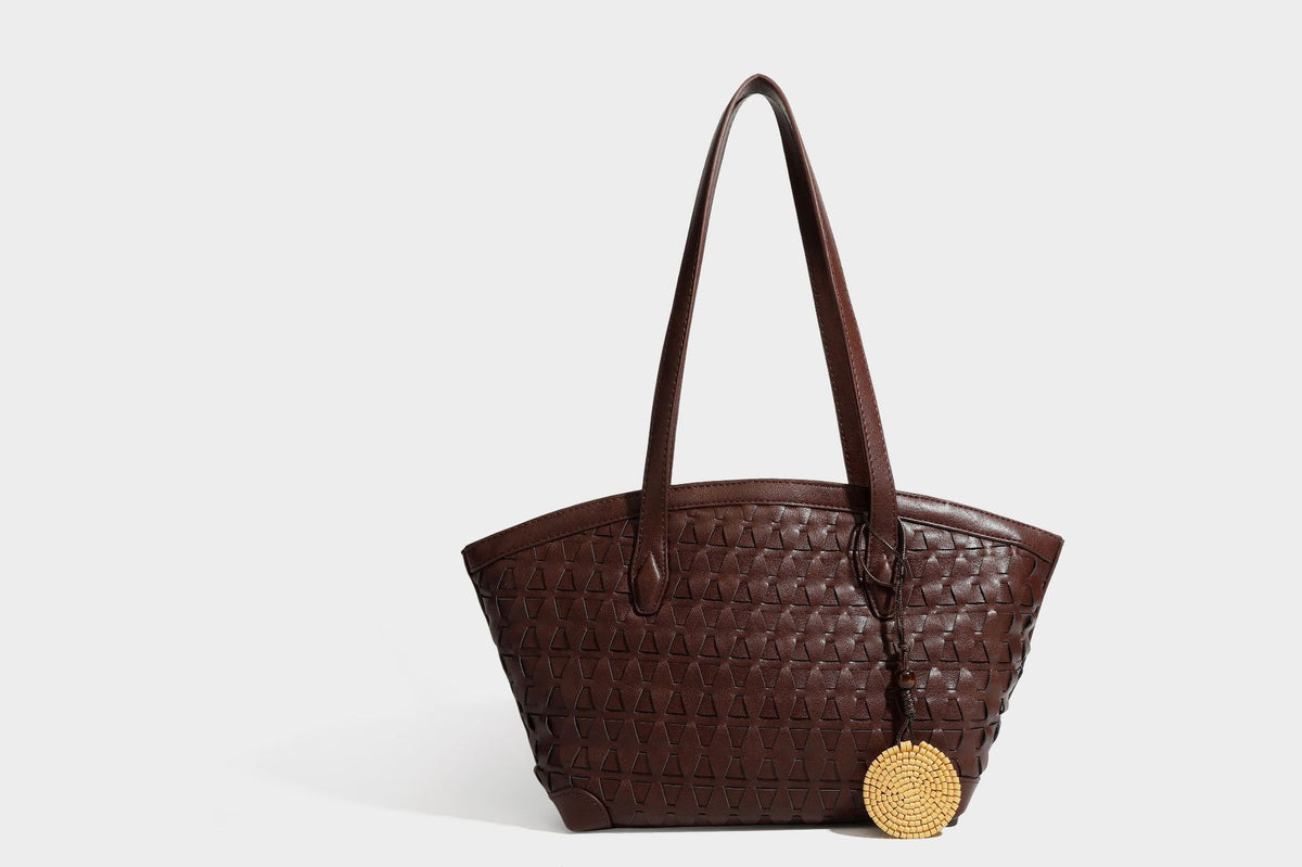 Large leather-look tote bag with geometric woven emboss, double shoulder straps, and round woven cord charm in brown, detail