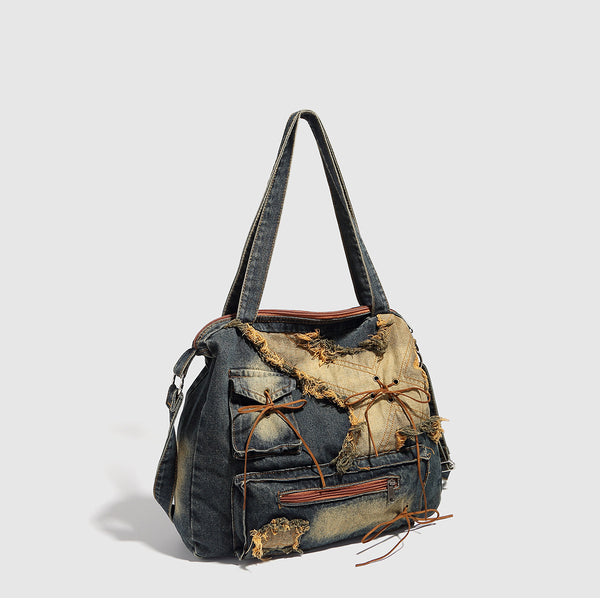 Large distressed denim patchwork shoulder tote bag with frayed panels, leather-look lace detailing, and front zip pocket in