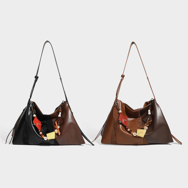 Two-tone black and brown leather-look slouchy shoulder bag with beaded tassel charm and silver-tone hardware, detail view 2